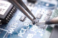 a pair of tweezers are working on a circuit board